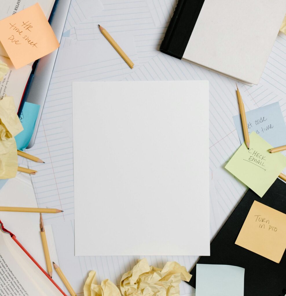 Cluttered desk with notebooks, a phone and unfinished notes, symbolizing the messy middle of growth and learning