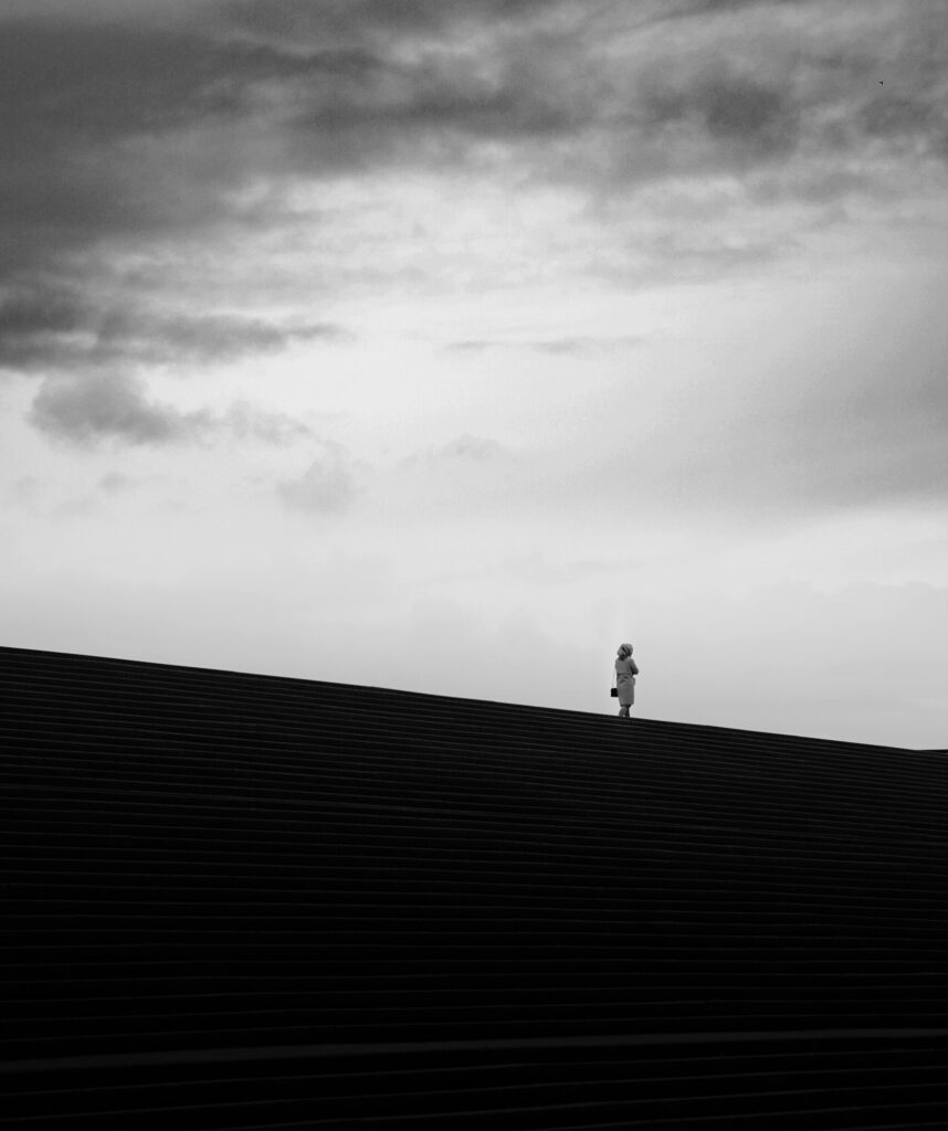 A person standing on the edge of a balcony looking outward, symbolizing the courage and uncertainty of taking first steps